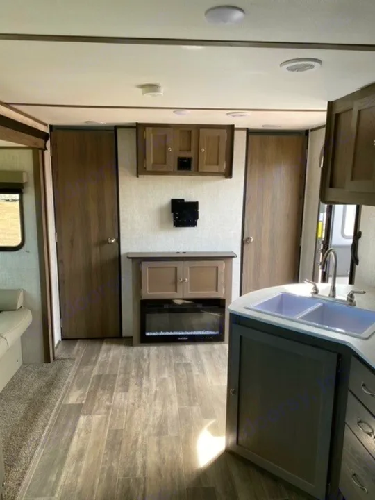 This RV rental's interior shows a modern living space with a kitchen sink, electric fireplace, and wood-look floor.. Gulf Stream Gulf Breeze 2023