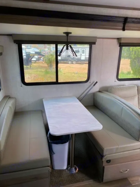 Explore this RV rental's inviting dinette, equipped with comfortable benches, a table, and scenic views through the windows.. Gulf Stream Gulf Breeze 2023