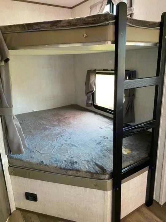 Spacious bunk beds in this cozy RV rental sleeping area, complete with a ladder and window, ideal for families and friends.. Gulf Stream Gulf Breeze 2023