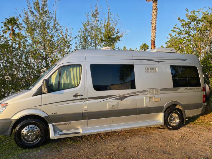 A sleek silver Pleasure-Way Plateau-FL Class B rv rental, parked outdoors on dirt, ready for your next adventure.. Pleasure-Way Pleasure-Way Class B 2013