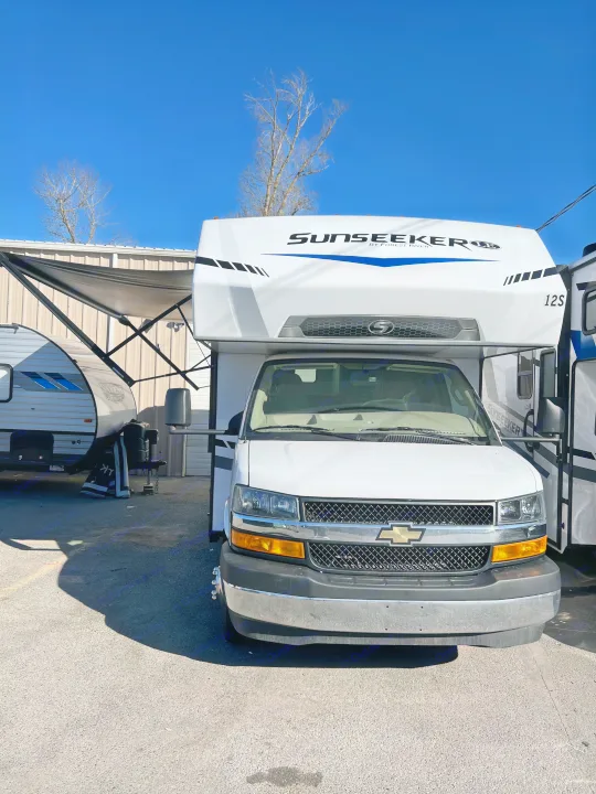 Front view of a white Sunseeker RV rental, a Class C motorhome, parked outdoors on a sunny day with another RV in the background.. Forest River Sunseeker 2025