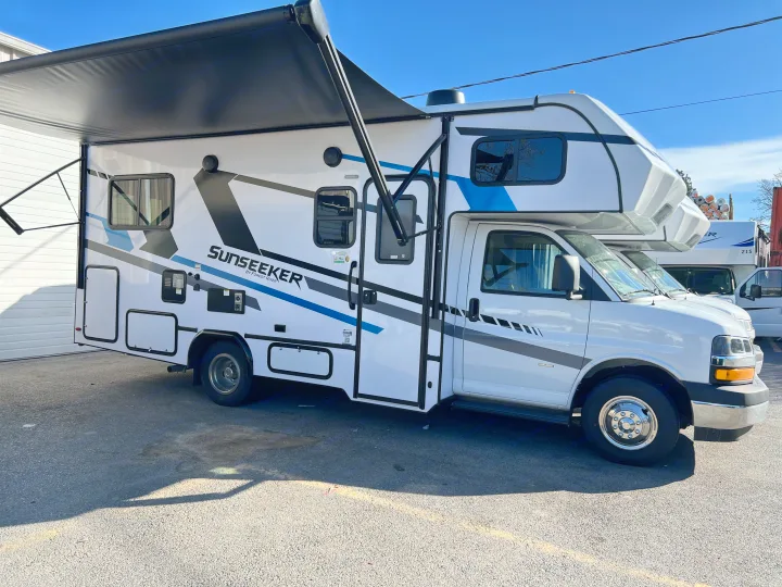 RV rental: A white Sunseeker motorhome with blue/black graphics, its awning extended, parked on asphalt for travel.. Forest River Sunseeker 2025