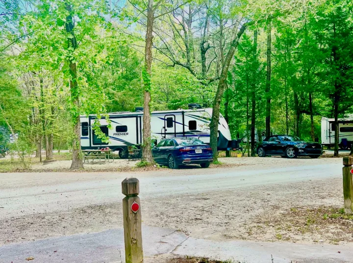 Lush campground scene with an RV rental, cars, and picnic area. Ideal for your next outdoor adventure.. Keystone RV Bullet Premier Ultra Lite 2022