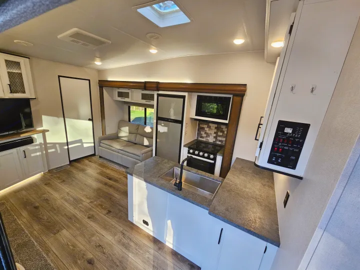 Bright, modern rv rental interior with kitchen, living area, sofa, and wood-look flooring.. Crusader Lite 2022