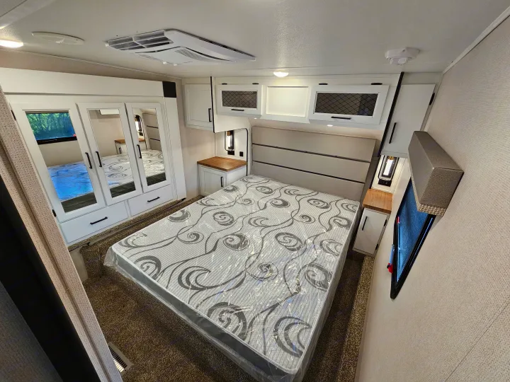 Well-equipped RV rental bedroom with a queen bed, mirrored closet, overhead storage, and integrated climate control.. Crusader Lite 2022