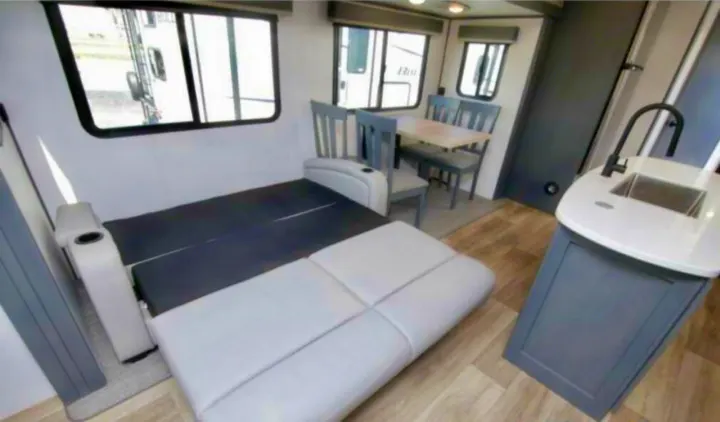 Interior of this RV rental features a convertible sofa/bed, dining area, and kitchen. A versatile living space for travel.. Keystone RV Bullet Premier Ultra Lite 2022