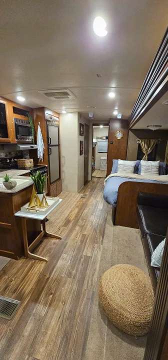 Bright, modern RV rental interior showing a full kitchen, comfortable bed, living space, and wood-look floors.. Forest River Vibe 2017