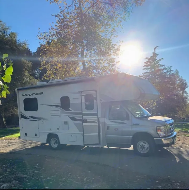 A modern white RV rental, parked on a sunny day with trees in the background, ready for adventure and travel.. Adventurer Adventurer Motorhome 2019