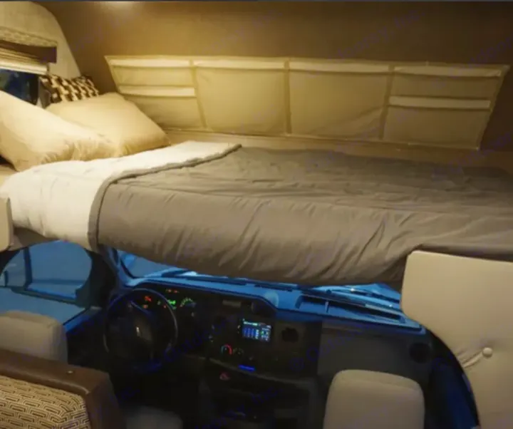 Comfortable over-cab bunk bed in an rv rental, with dashboard visible below. Ideal for a cozy travel adventure.. Adventurer Adventurer Motorhome 2019