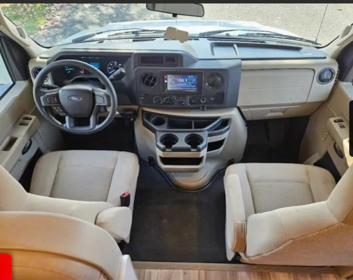 Spacious RV rental cockpit with driver and passenger seats, dashboard, and infotainment system.. Thor Freedom Elite 2022