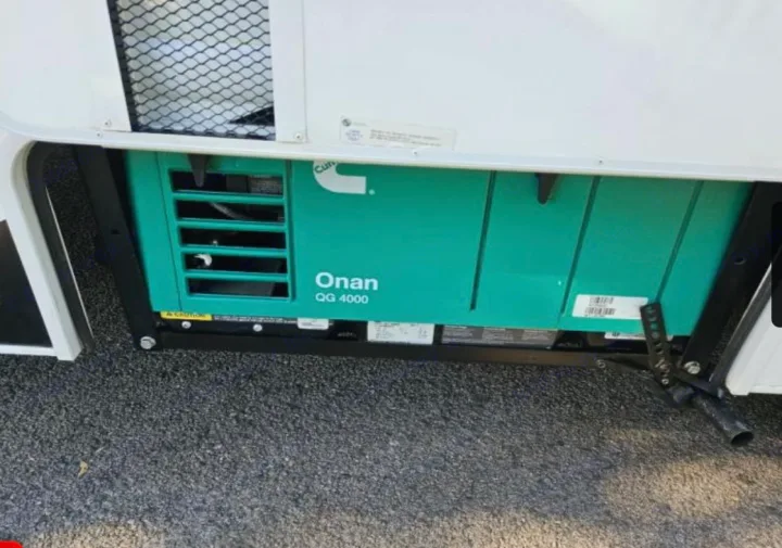 Green Onan QG 4000 generator mounted on an RV, essential for your next RV rental. Provides power on the go.. Thor Freedom Elite 2022