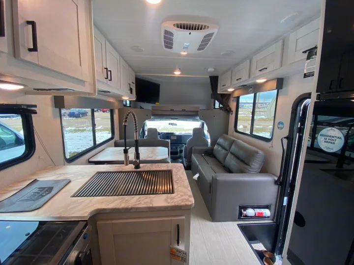 Bright rv rental interior, highlighting the modern kitchen, comfortable sofa, and front cab area. Great for travel.. East to West Entrada 2025