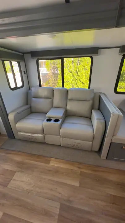 Experience comfort in this RV rental! Interior features a cozy gray recliner sofa with cup holders and large windows.. Keystone RV Bullet Premier Ultra Lite 2022