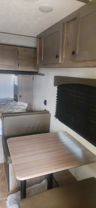 A bright RV rental interior showing the dinette, bed, and storage cabinets, ideal for a comfortable trip.. Sunset Park RV Sun Lite 2024