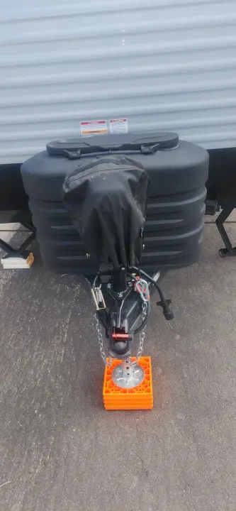 RV rental ready: The front hitch, covered propane tanks, safety chains, and jack stand on bright orange blocks.. Sunset Park RV Sun Lite 2024