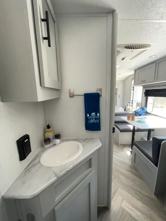 Inside a modern rv rental: bright bathroom with sink & towel, flowing into a comfortable dinette and living space.. Forest River Salem FSX PLATINUM 2021
