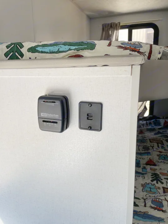 RV rental bunk area with a Suburban thermostat and USB ports for climate control and device charging, featuring nature-themed bedding.. Forest River Salem FSX PLATINUM 2021