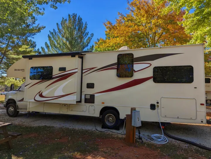 Redhawk RV rental at a picturesque campsite with autumn trees. Fully hooked up & slide-out extended, ready for adventure.. Jayco Redhawk 2015