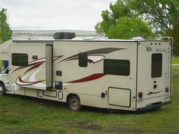 Spacious Jayco Redhawk RV rental parked at a scenic campsite with a lake view, perfect for your next road trip adventure.. Jayco Redhawk 2015