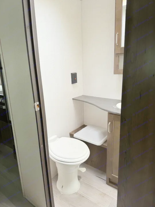 Step inside a cozy rv rental bathroom featuring a compact toilet, vanity with sink, and a convenient GFI outlet.. Keystone RV Passport SL 2021