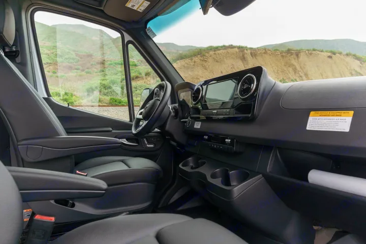 The modern driver's cabin of an RV rental van, featuring a spacious dashboard, steering wheel, and comfortable seating.. Coachmen Prism 2023