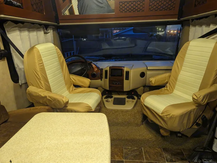 RV rental interior: A clean, inviting front cab with dual covered seats, dashboard, and windshield view.. Thor Other 2014