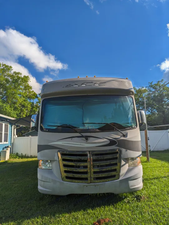 Front view of a gray RV rental parked on a sunny lawn, ready for adventure under a blue sky.. Thor Other 2014