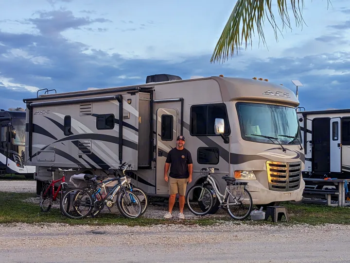 Enjoying leisure in an RV rental: a man stands by his Class A motorhome with bicycles at a campsite.. Thor Other 2014