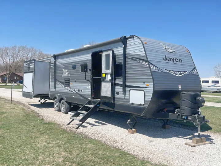 This Jayco travel trailer, perfect for an RV rental, is set up at a sunny campsite. A home on wheels ready for adventure.. Jayco Jay Flight 2020