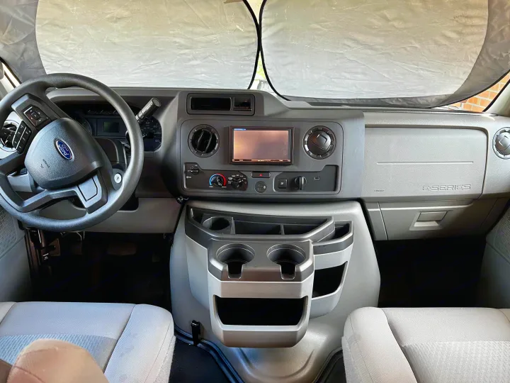 Inside a modern RV rental, showing the Ford E-Series dashboard, steering wheel, and a protective windshield sunshade.. 1FDXE4FN9RDD14726 3100FB 2023