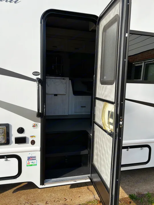 Open entry door of a white RV, revealing interior steps and kitchenette. Ready for your next rv rental adventure!. 1FDXE4FN9RDD14726 3100FB 2023