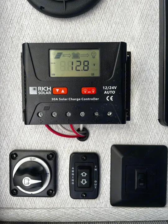 Essential RV rental controls: solar charge controller displaying 12.8V, battery switch, and awning buttons for operation.. 1FDXE4FN9RDD14726 3100FB 2023