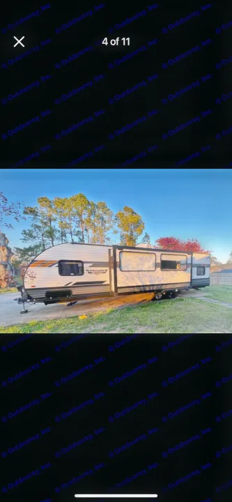 Side view of a parked Wildwood travel trailer RV rental with slide-out extended, under a clear sky.. Forest River Wildwood X-Lite 2021