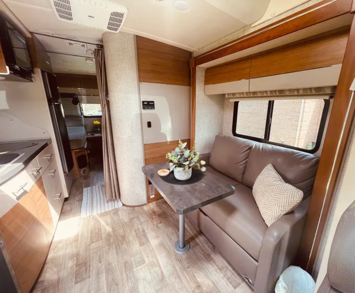 Cozy RV rental interior: kitchen, living area with couch & table, and bedroom beyond. Modern, compact, and well-lit.. Winnebago View 2016