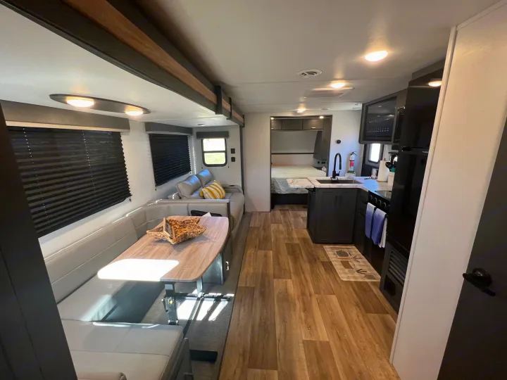 Spacious RV rental interior with dining booth, full kitchen, and bedroom view. Perfect for travel!. Keystone Bullet Crossfire 4YDTBLN25RD430760 2024