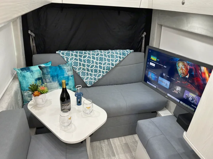 RV rental interior featuring a cozy lounge area with TV, wine, and comfortable seating, ideal for relaxation.. Pleasure-Way Pleasure-Way Class B 2024