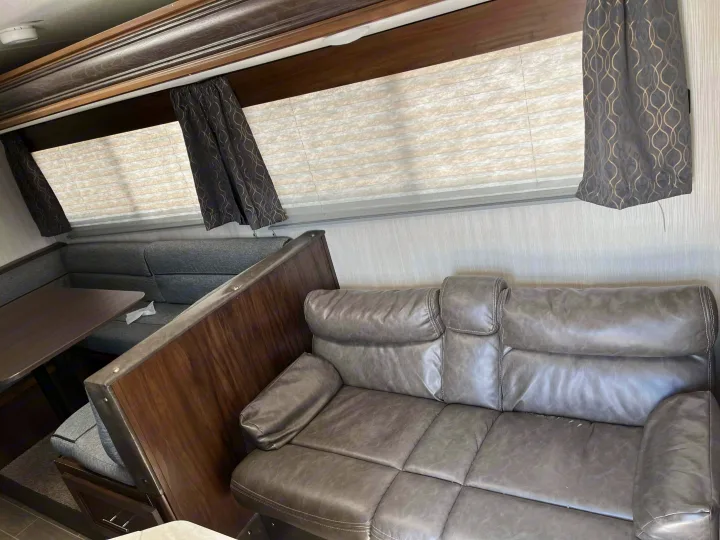 RV rental interior: comfy gray sofa & dinette with table. Windows have blinds/curtains. A cozy, functional living space.. Forest River Cherokee Grey Wolf 2020