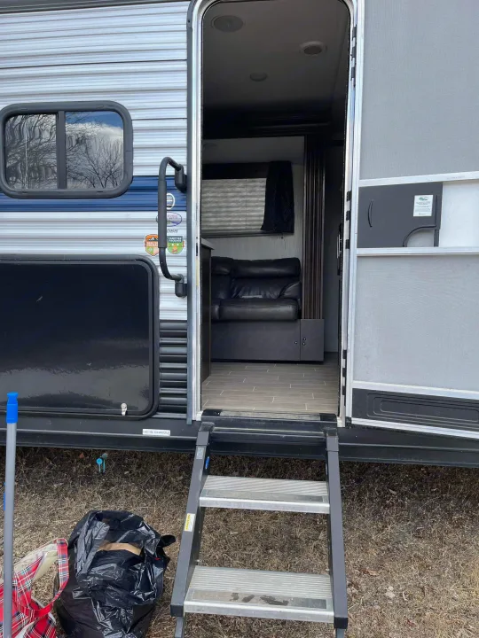Open door and steps of an RV rental, revealing its cozy interior with dark leather seating. Your next adventure awaits!. Forest River Cherokee Grey Wolf 2020