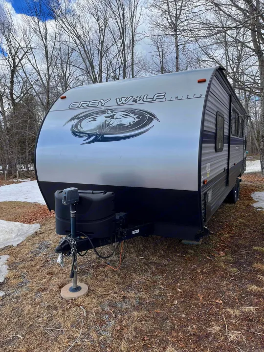 Grey Wolf Limited travel trailer for your next RV rental adventure. Silver and black RV parked outdoors among bare trees with patches of snow.. Forest River Cherokee Grey Wolf 2020