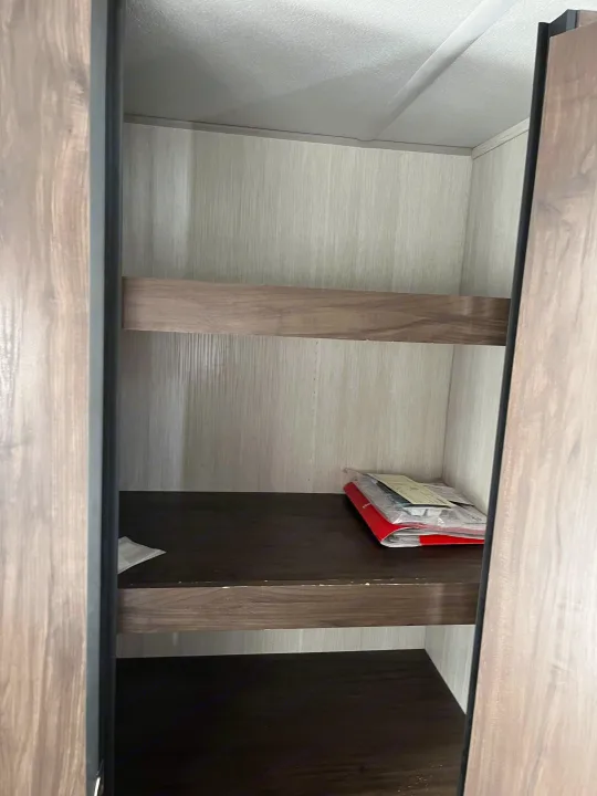Peek inside an RV rental's organized cabinet with shelves holding owner's manuals. Clean and ready for your gear.. Forest River Cherokee Grey Wolf 2020