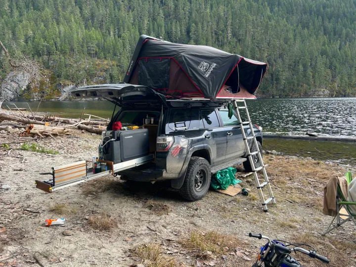 This RV rental-style setup offers adventure: a 4Runner with a rooftop tent & portable kitchen by a scenic lake.. Toyota Other 2015