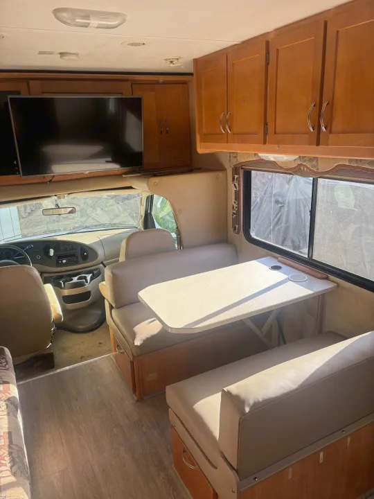 Spacious RV rental interior: dinette, TV, cockpit, and ample storage, ready for your next adventure.. Forest River Sunseeker 2009