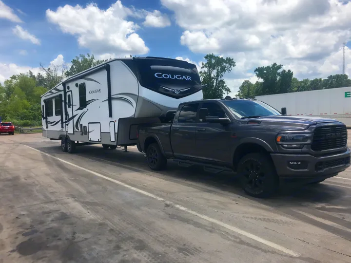 Heavy-duty pickup truck towing a large white Cougar fifth-wheel RV. Great for an rv rental road trip!. Keystone Cougar 2022