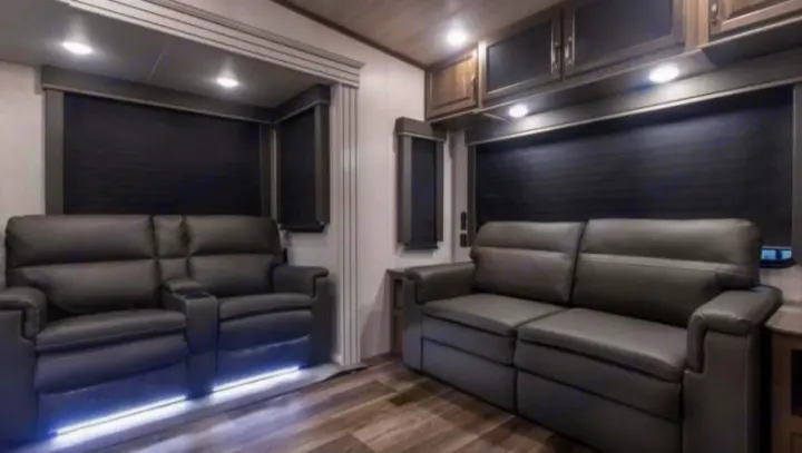 This cozy rv rental living room features comfortable recliners with under-lighting, a sofa, dark blinds, and wood flooring.. Keystone Cougar 2022