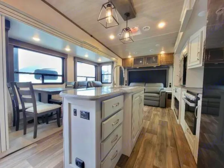 Spacious, modern RV rental interior with a fully equipped kitchen, dining area, and living room, bathed in natural light.. Keystone Cougar 2022