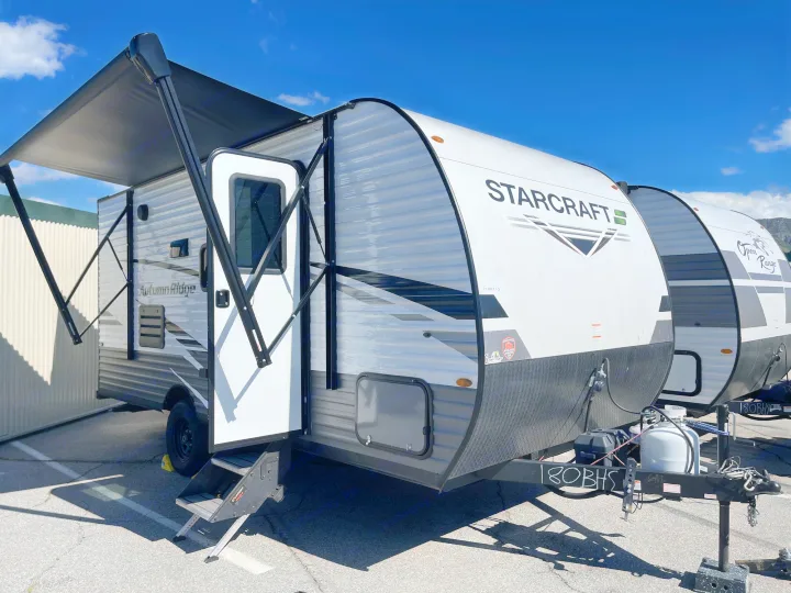 STARCRAFT Autumn Ridge rv rental: A white and black travel trailer with an extended awning, parked outside. Perfect for adventures!. Starcraft Autumn Ridge 2023