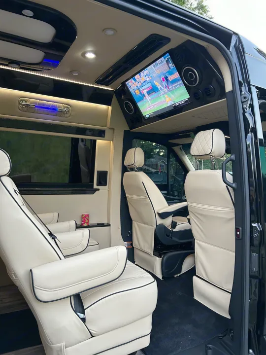 Luxurious rv rental interior: Enjoy plush cream seating, a large TV showing baseball, and ambient lighting in this premium mobile lounge.. Mercedes-Benz Sprinter 2024
