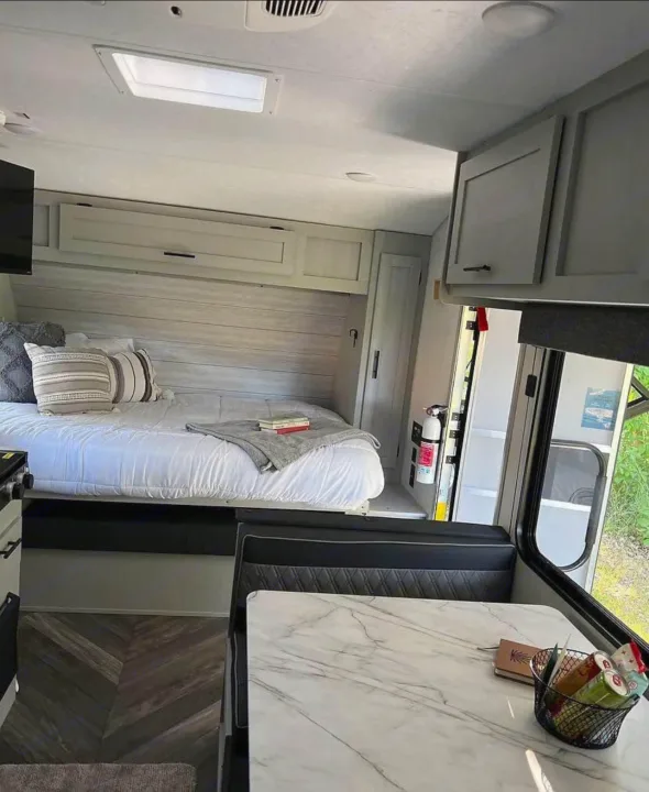 Bright, modern rv rental interior with bed, dining booth, kitchen, and ample storage for comfortable travel.. Forest River Wildwood FSX Plantium 2022