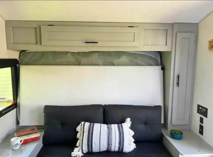 Inside a modern RV rental, a comfy sofa converts to a bed, with ample storage & amenities for a pleasant trip.. Forest River Wildwood FSX Plantium 2022
