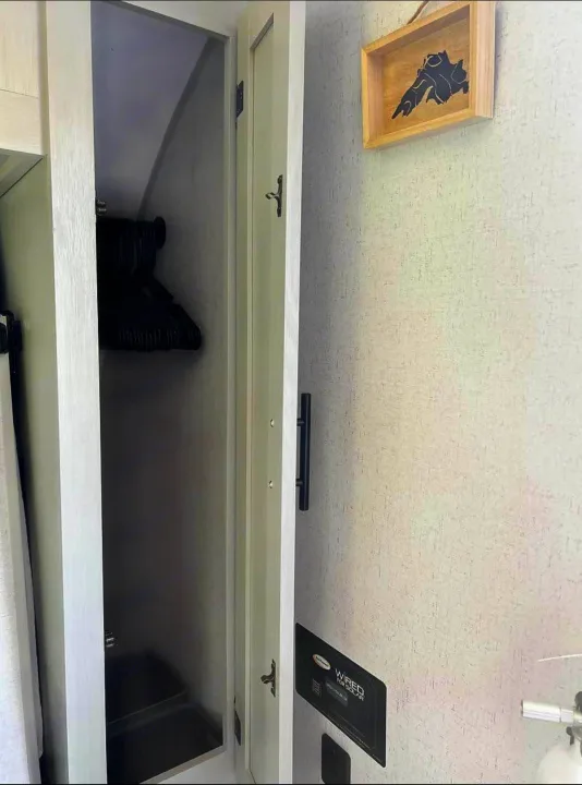 An RV rental's organized interior features an open closet with hangers, a "Wired for Solar" panel, and wall art.. Forest River Wildwood FSX Plantium 2022